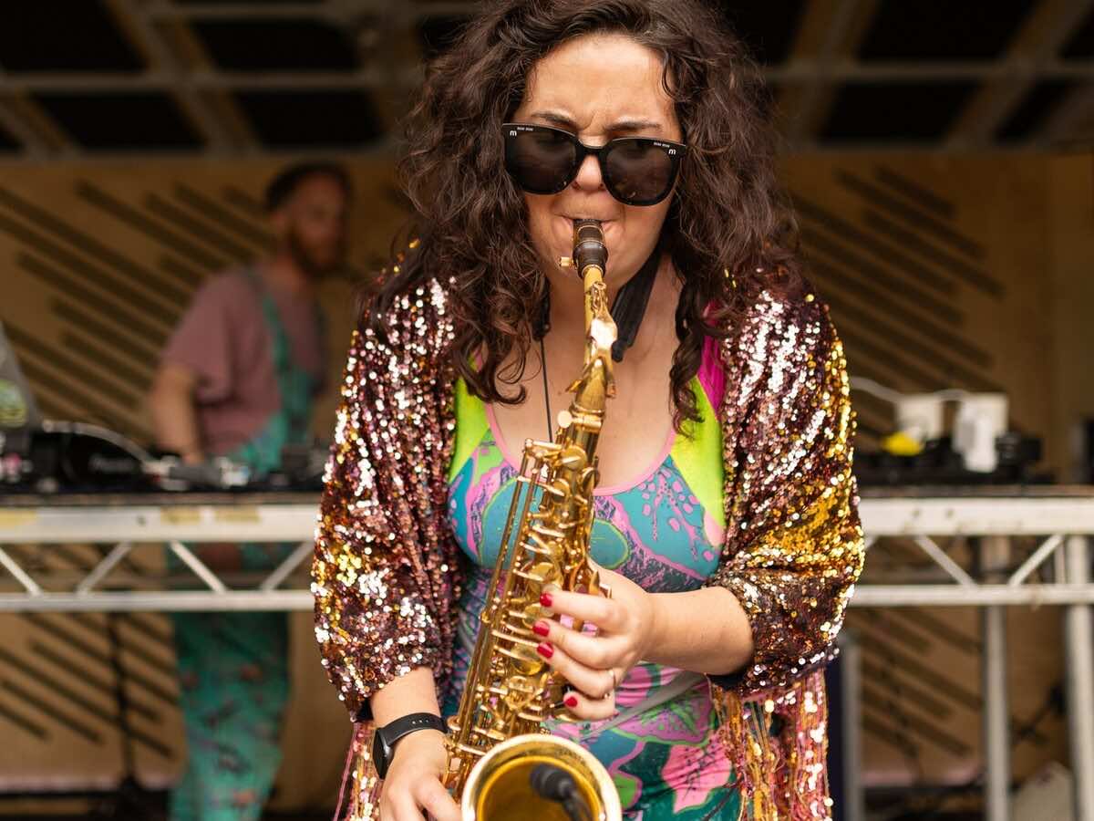 A saxophonist in a sequinned jacket performing on stage